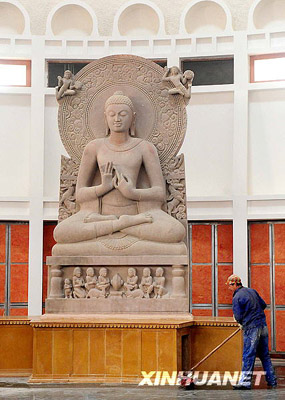 Un ouvrier en train de nettoyer la base d'une statue de bouddha importée d'Inde