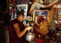 Un moine tibétain prépare des offrandes devant une photo du dalaï lama, le leader spirituel exilé en Inde.