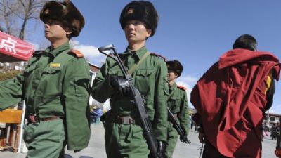Des soldats de l'armée chinoise croisent un moine tibétain au cours d'une patrouille dans les rues de Lhassa, le 1er février 2009, pendant la célébration du nouvel an chinois par les colons chinois installés au Tibet.