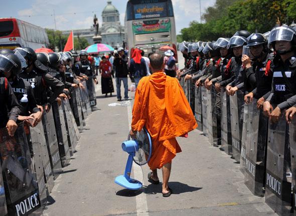 Un moine bouddhiste thaïlandais passe devant des rangées de policiers après une manifestation anti-gouvernementale à Bangkok, le 14 avril 2009.