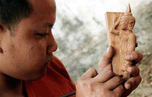 LUANG PRABANG, Laos: Lao monk displays a wooden carving of a Buddha