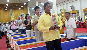 People standing in prayer after emerging from coffins at Wat Prommanee. Some people have performed the ritual several times.