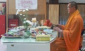 Un des moines bouddhistes exécute une prière avant d'offrir les bonbons aux enfants.