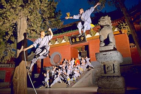 Devant le temple de Shaolin, les moines guerriers prennent des postures empruntées au vaste répertoire de Shaolin. Au sommet de l'escalier, au centre, se tient Shi Yong Xin, le supérieur du temple.