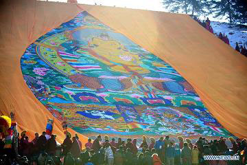 Lamas unveil a gigantic Buddha tangka alongside a hillside for disciples' worship in Labrang Monastery in Xiahe, northwest China's Gansu Province, Feb. 22, 2013.