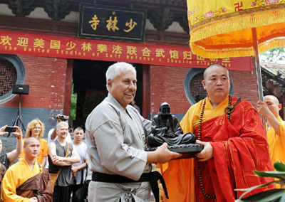 Shi Yongxin (à dr.), abbé du temple Shaolin, a présenté, le 3 juillet, une statue de Bouddha Dharma à un membre du United Studio of Self Defense (USSD), dans le district de Dengfeng, ville de Zhengzhou, province du Henan. [Photo/Xinhua]