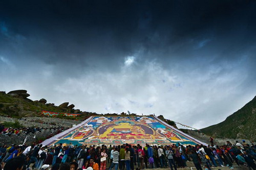 Des visiteurs admirent un thangka géant sur la montagne située derrière le monastère Drepung à Lhasa, capitale de la Région autonome du Tibet, le 6 août 2013.