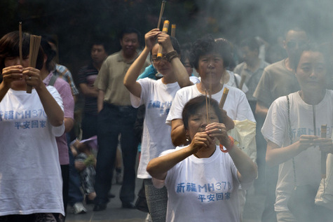 Des proches des passagers disparus du vol MH370 brûlent de l’encens et prient, à Pékin.