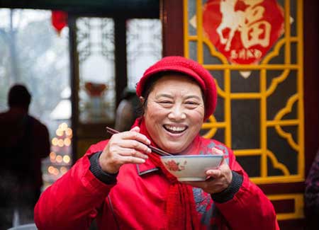 Une femme savoure un bol de bouillie La Ba à Nanjing, province du Jiangsu, le 8 janvier 2014.