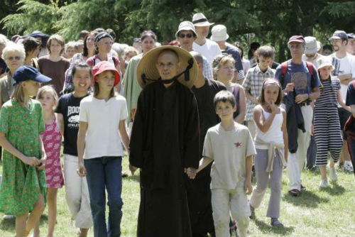 Thich Nhat Hanh se rend avec des enfants au temple bouddhiste du village des Pruniers, en marge d’une rencontre avec plusieurs centaines de personnes de différentes nationalités (photo archives AFP)