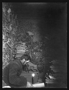 Paul Pelliot dans la grotte des livres par Charles Nouette. Chine, province du Gansu, Dunhuang, grotte aux manuscrits, entre le 25 février et le 27 mai 1908. Epreuve à la gélatine sur papier.